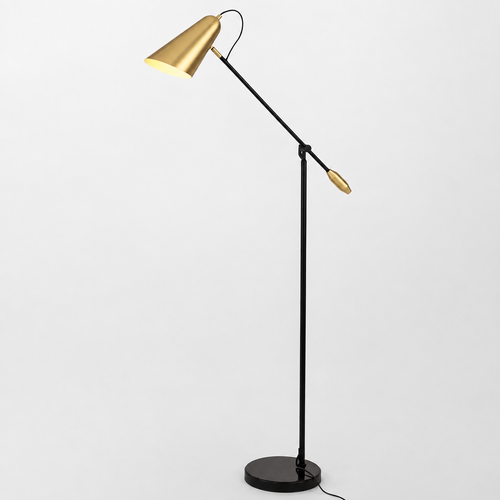 A modern adjustable floor lamp with a black metal stand and arm, featuring a conical gold lampshade and a small gold accent piece, set against a plain light gray background.