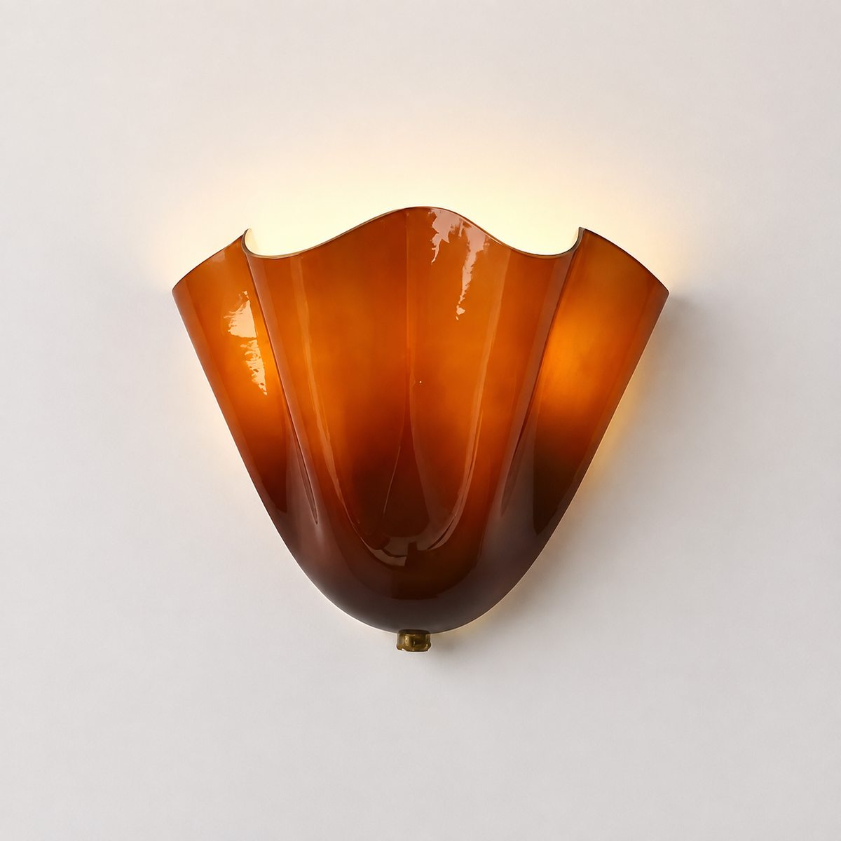 A vintage-style amber glass wall sconce with a wavy, flared shade, mounted on a plain off-white wall and casting a warm light upward.